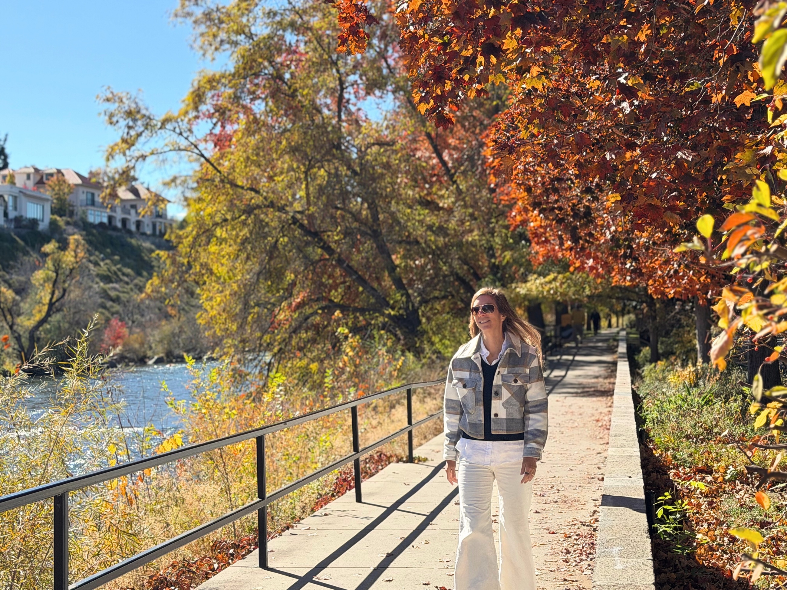 Stephanie walking beside the Truckee River beneath autumn trees in Reno.