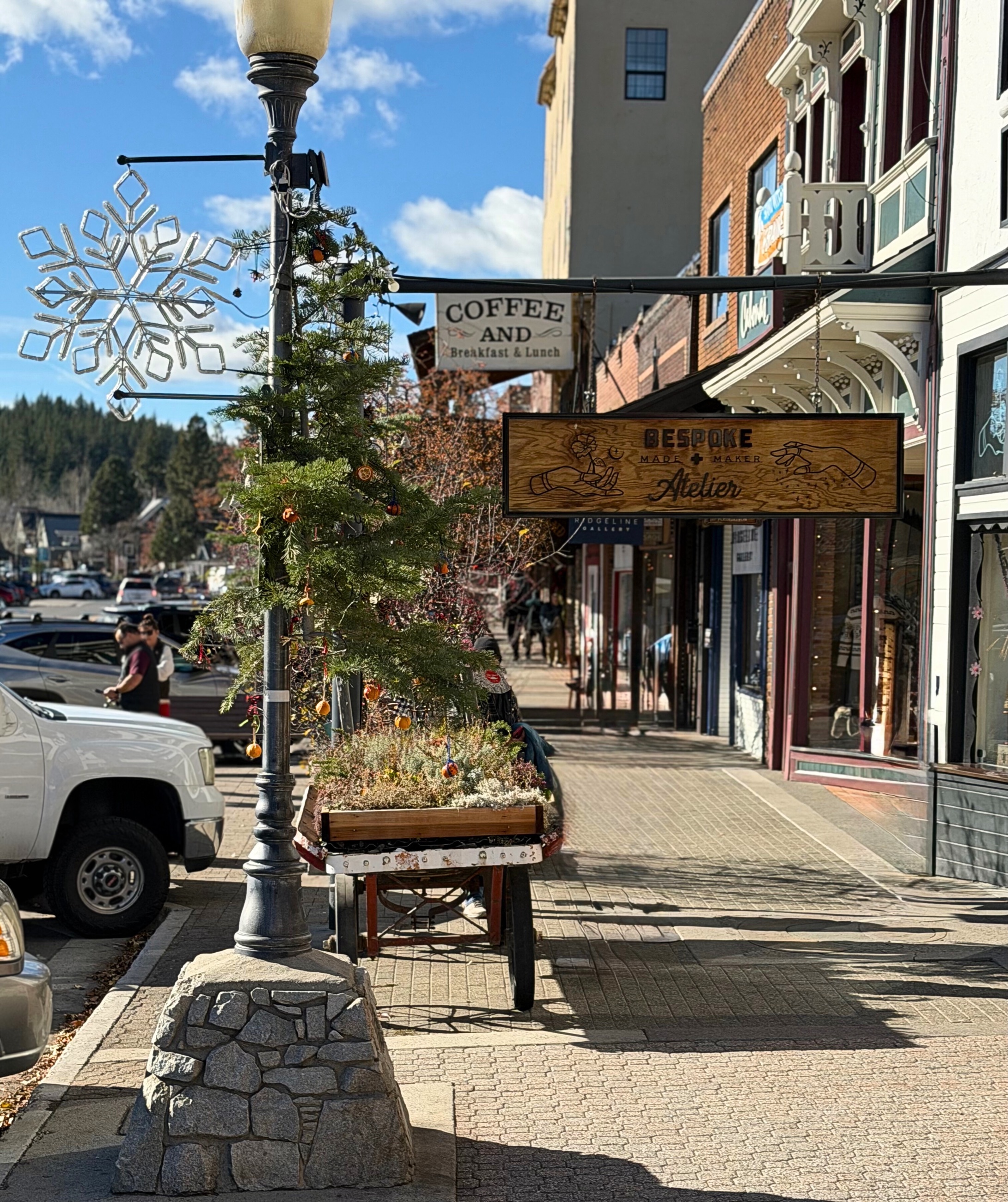 A downtown Truckee sidewalk decorated with a Christmas tree and snowflake lights.