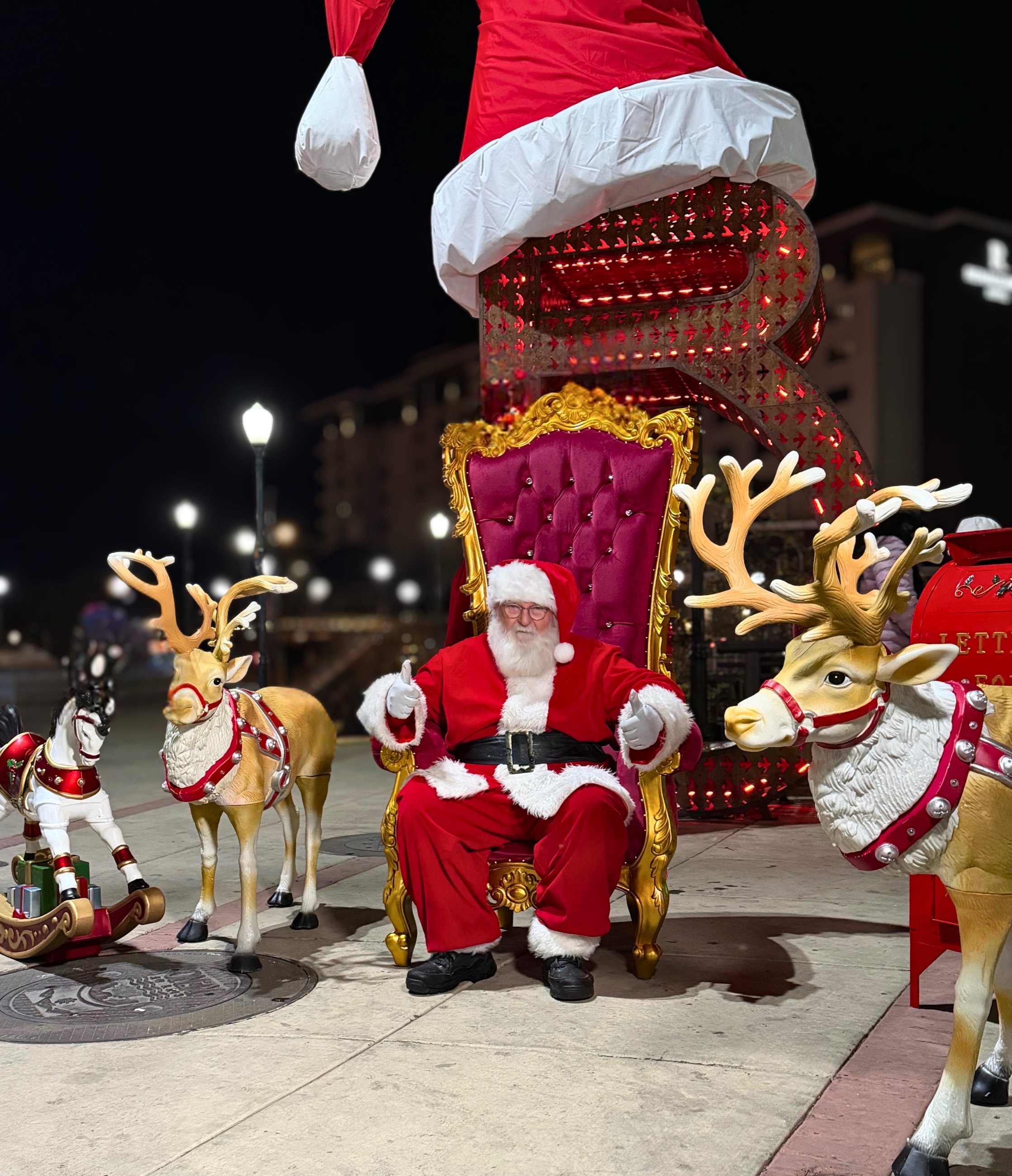 Santa seated between decorative reindeer at Reno City Plaza.