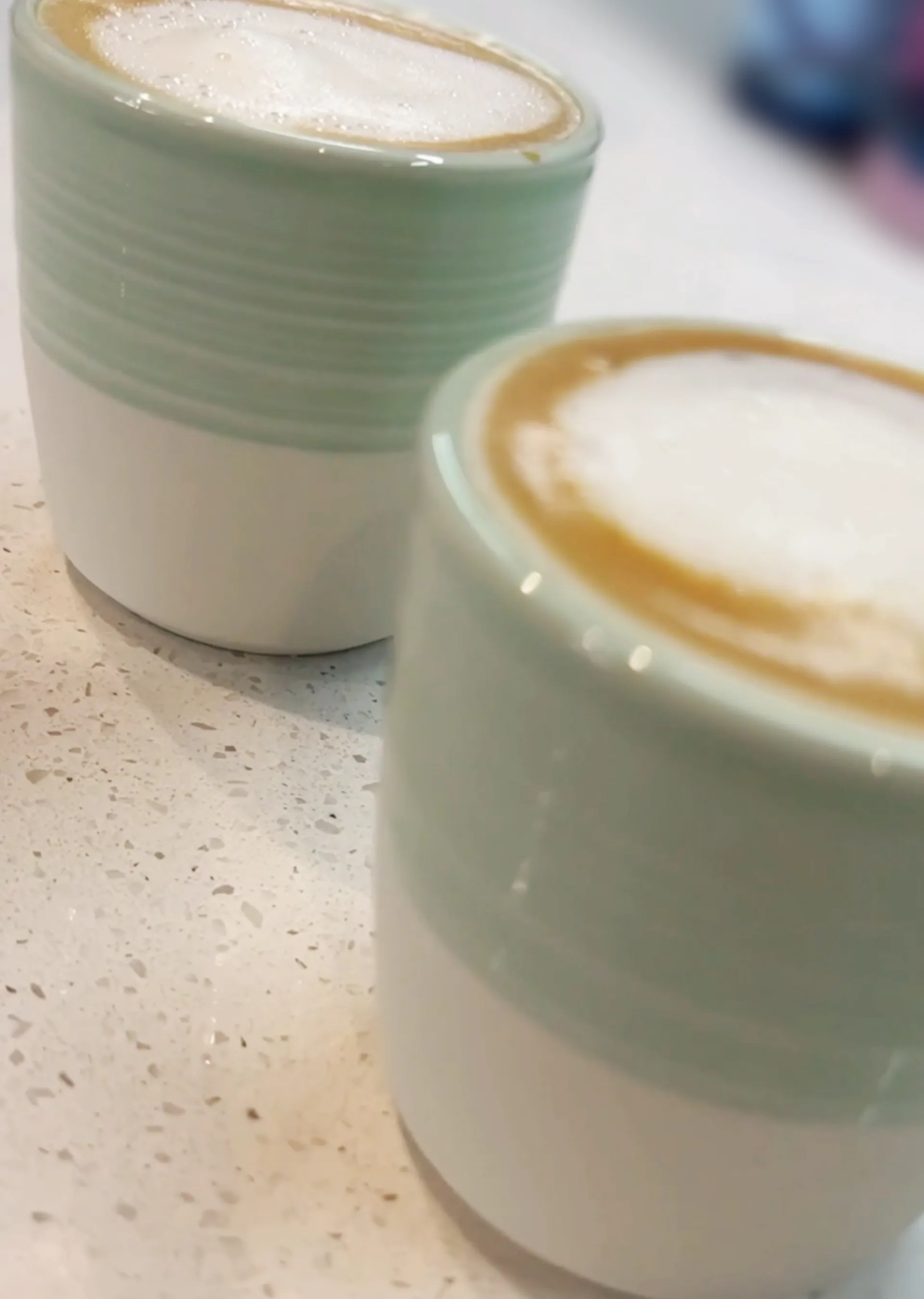 Two homemade flat whites on a kitchen counter