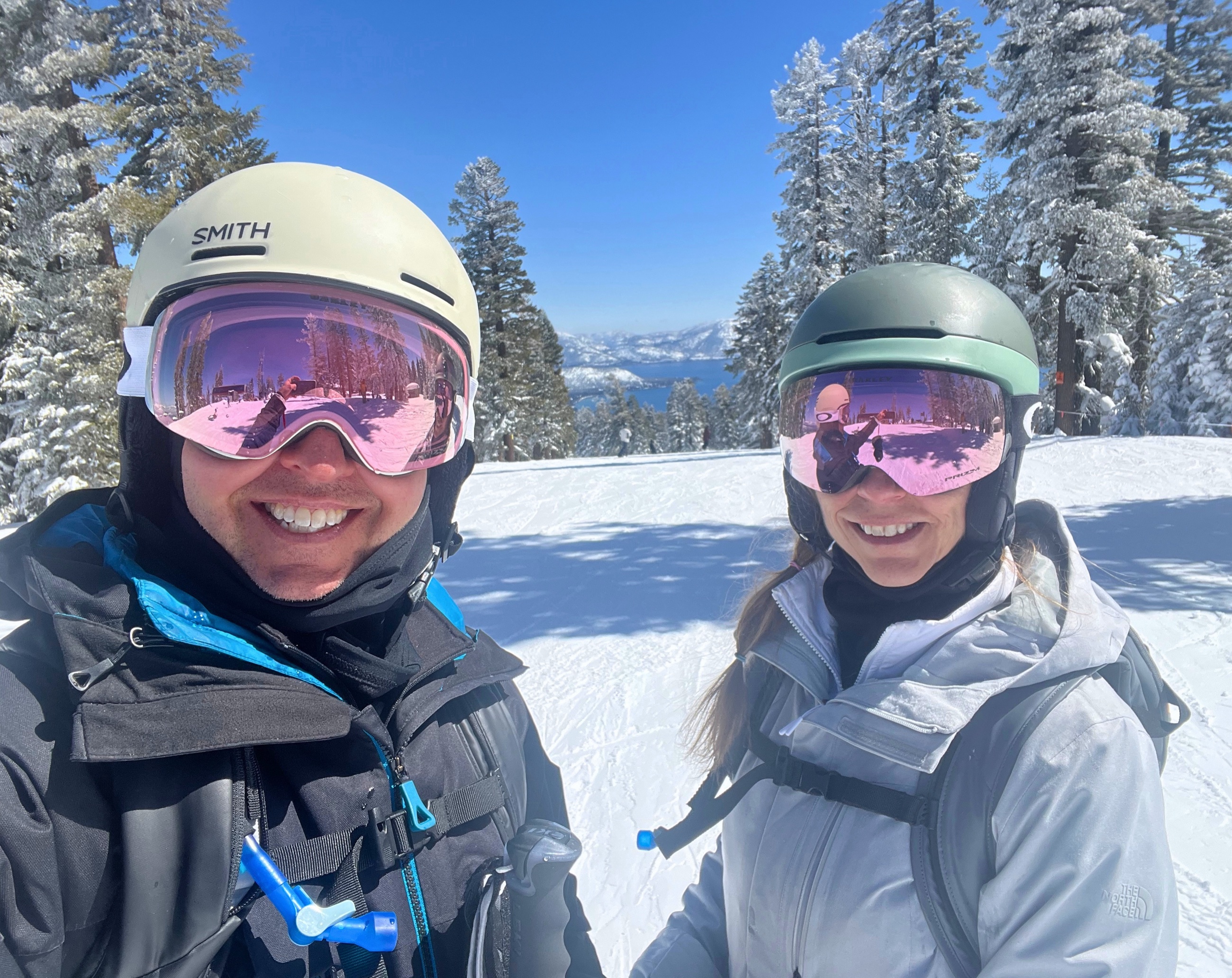 Sam and Stephanie skiing with Lake Tahoe visible beyond the slope