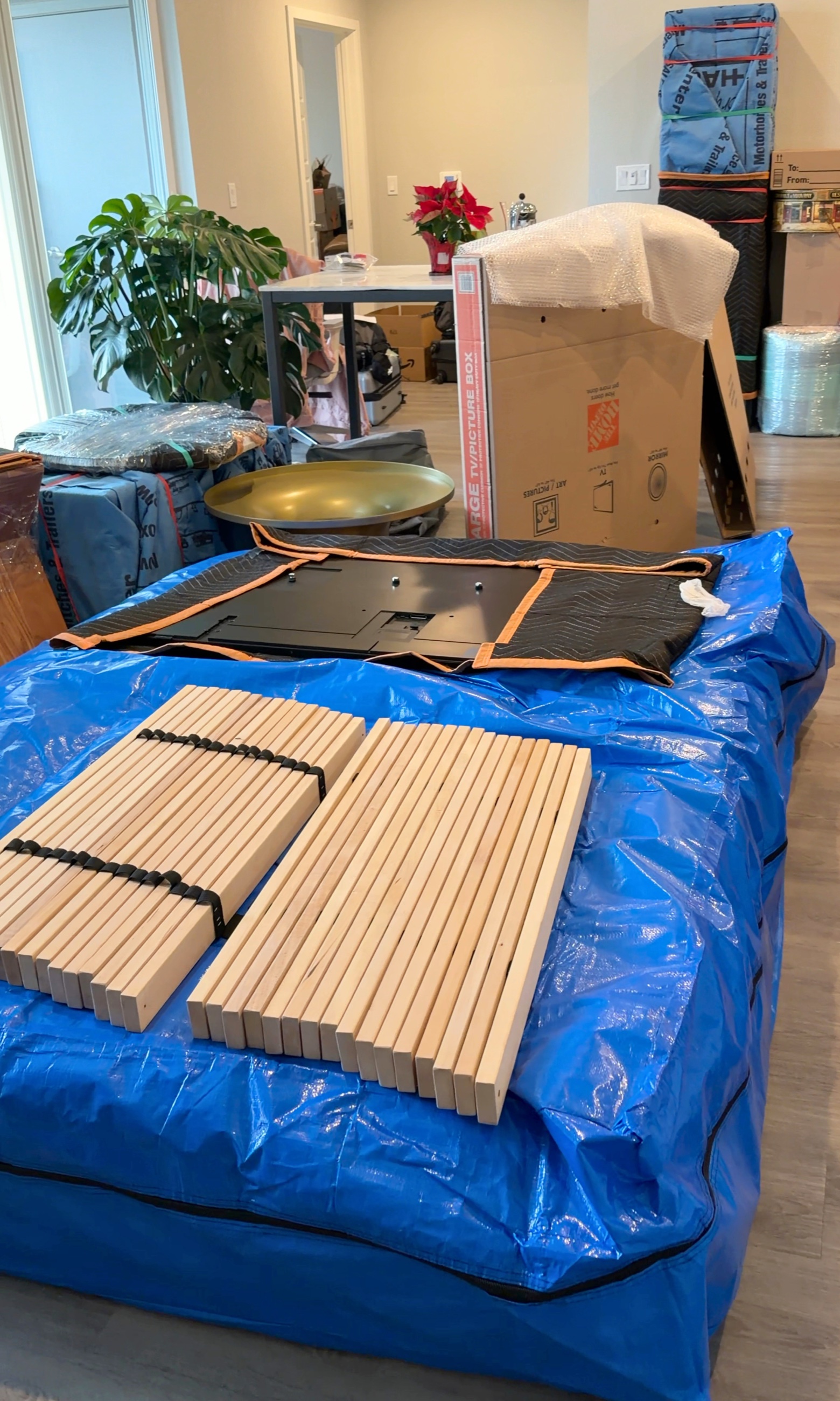 A Reno apartment living room filled with moving materials, a wrapped television, and household items being prepared for departure.