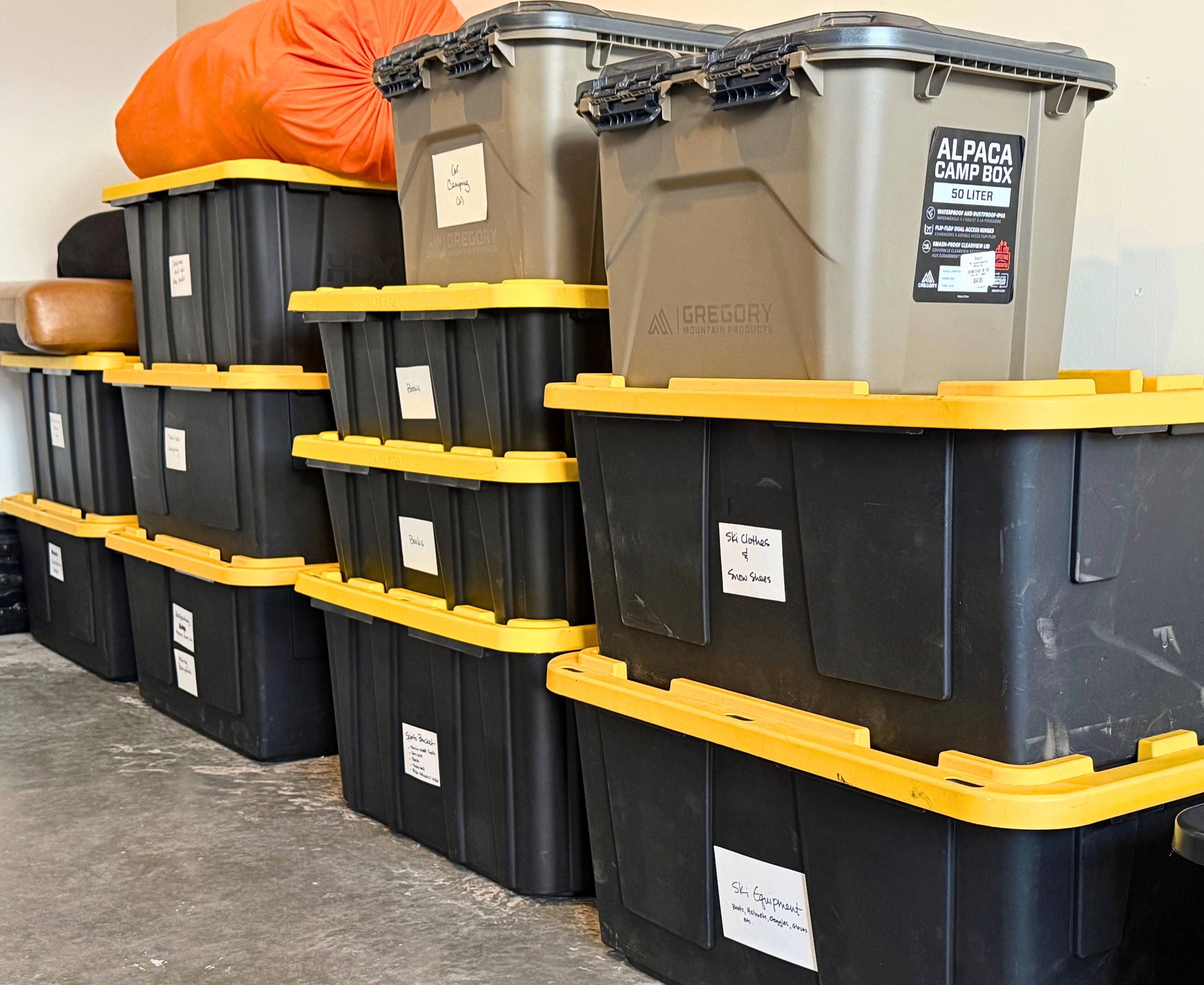 A wall of labeled black storage bins stacked inside the garage before the move.