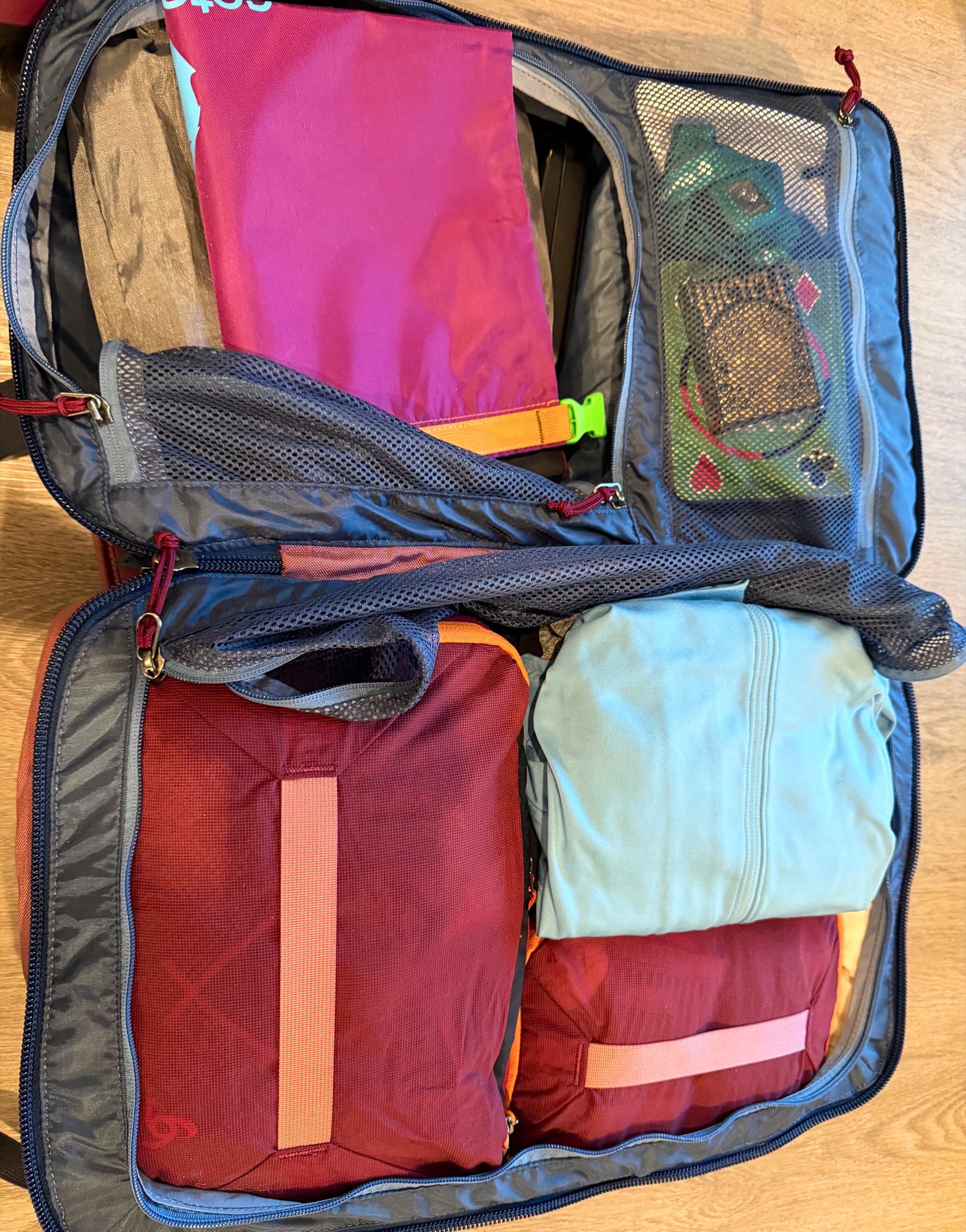 An open suitcase filled with packing cubes, clothing, and travel items during a full packing test.