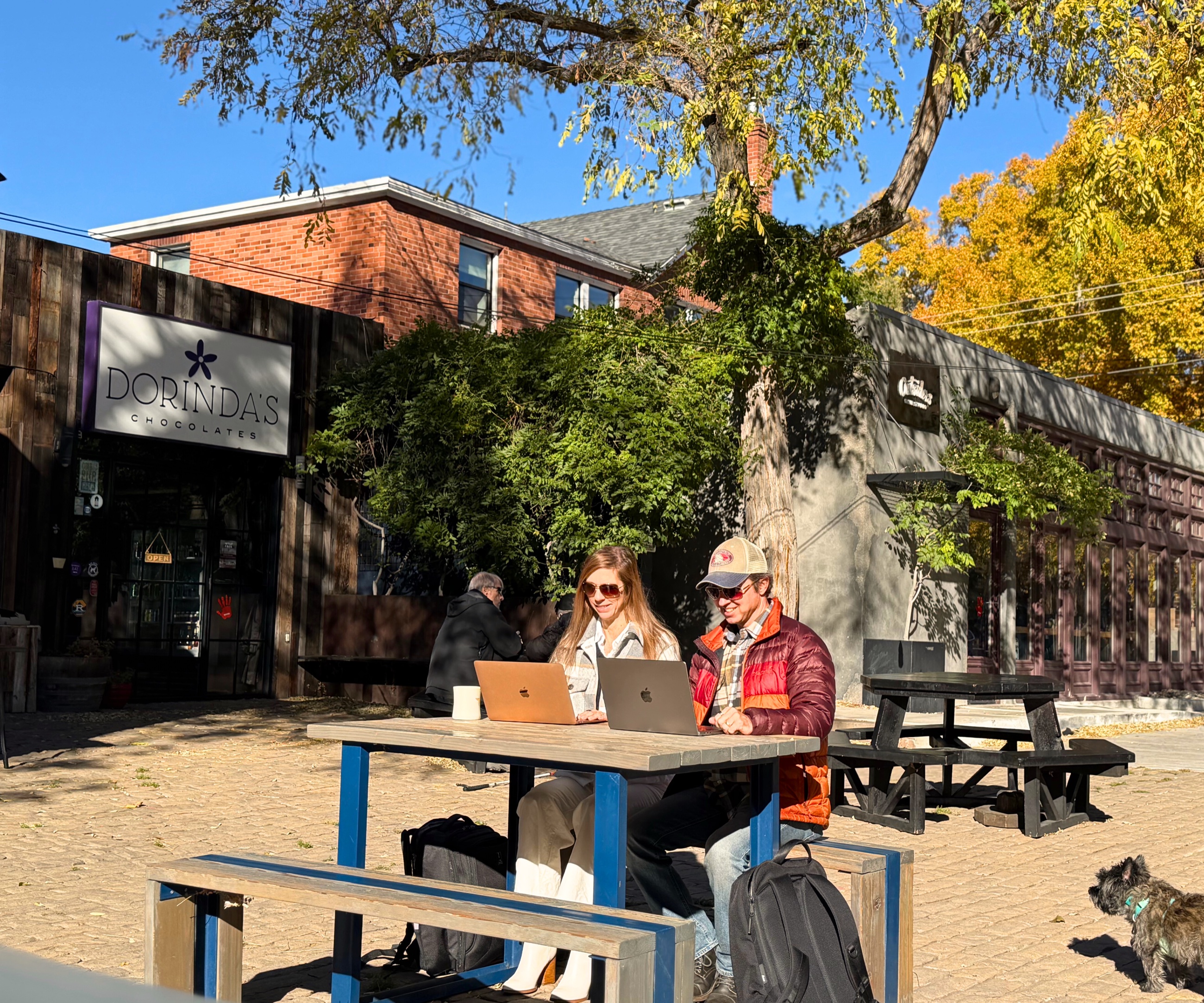 Sam and Stephanie working on laptops together at an outdoor table beside Dorinda's Chocolates in Reno.