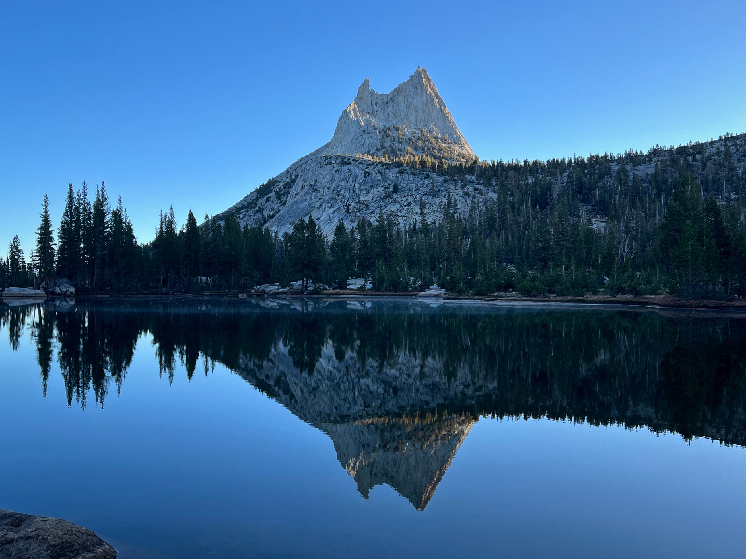 Cathedral Peak reflected in the still water of an alpine lake in Yosemite National Park.
