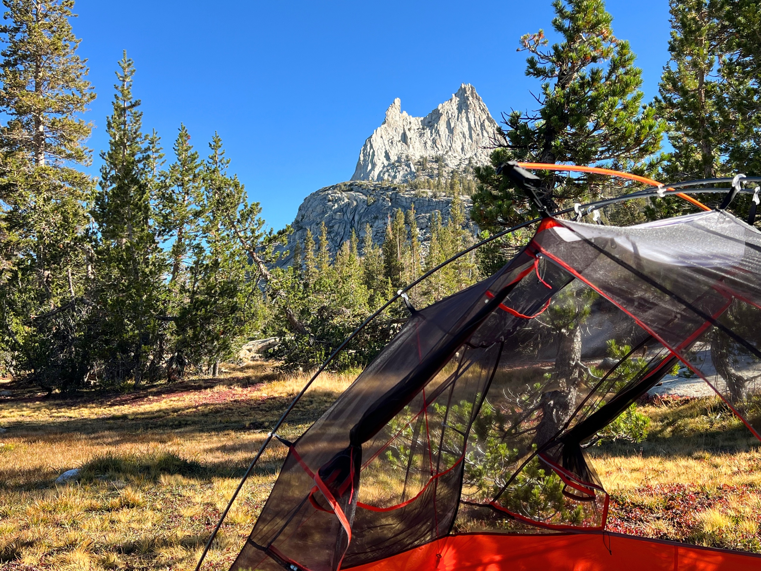 A backpacking tent set up near Cathedral Lakes with Cathedral Peak rising behind it.