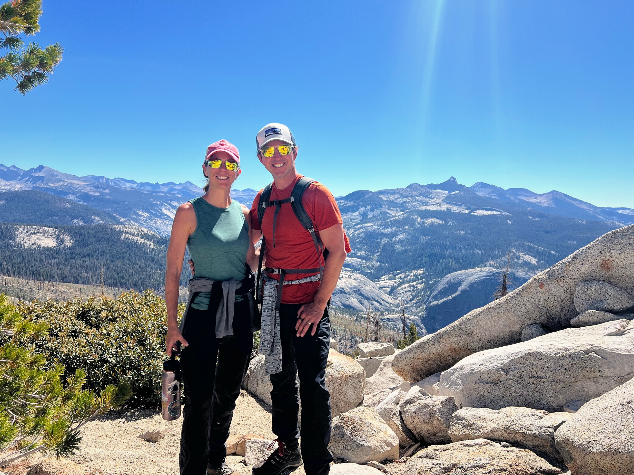 Sam and Stephanie standing near Clouds Rest with the Sierra Nevada behind them.