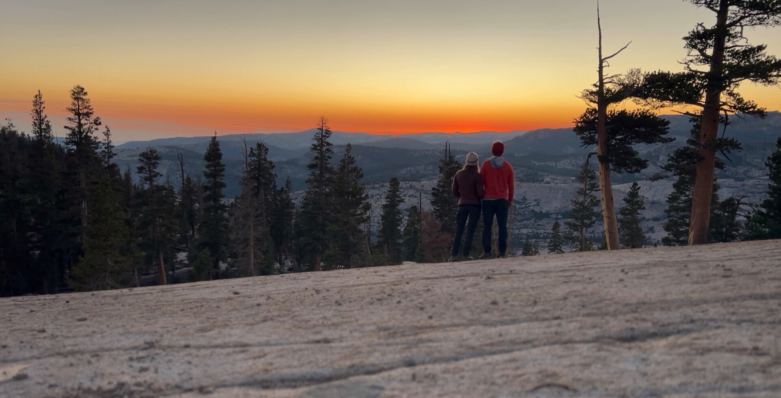 Sam and Stephanie standing on granite at sunset in Yosemite’s high country.