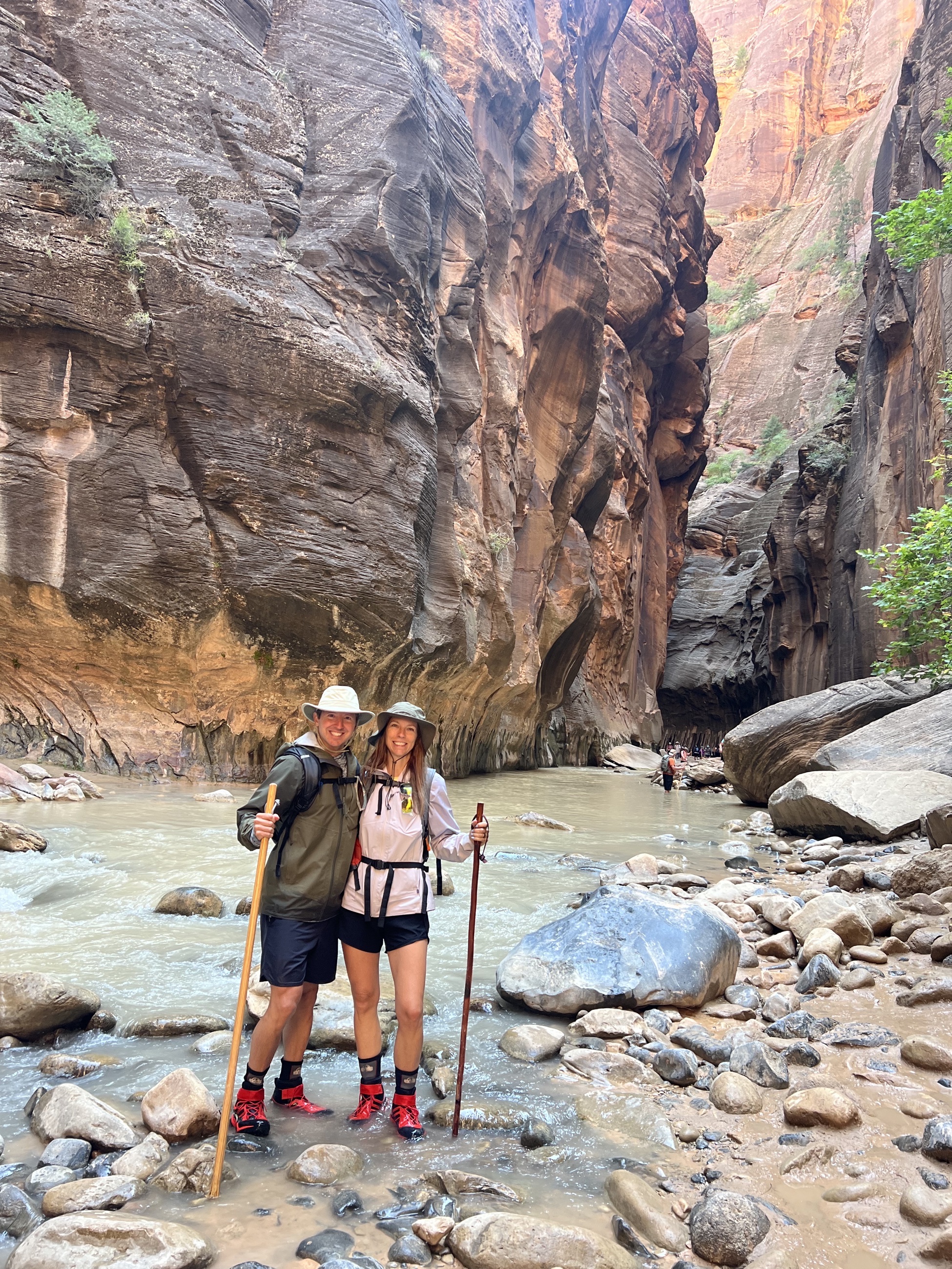 Sam and Stephanie standing in the Narrows in rented river gear at Zion National Park.